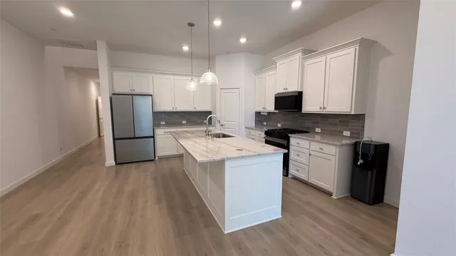 a kitchen with stainless steel appliances granite countertop a stove top oven a refrigerator and a sink