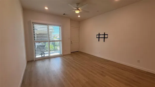 an empty room with wooden floor chandelier fan and windows