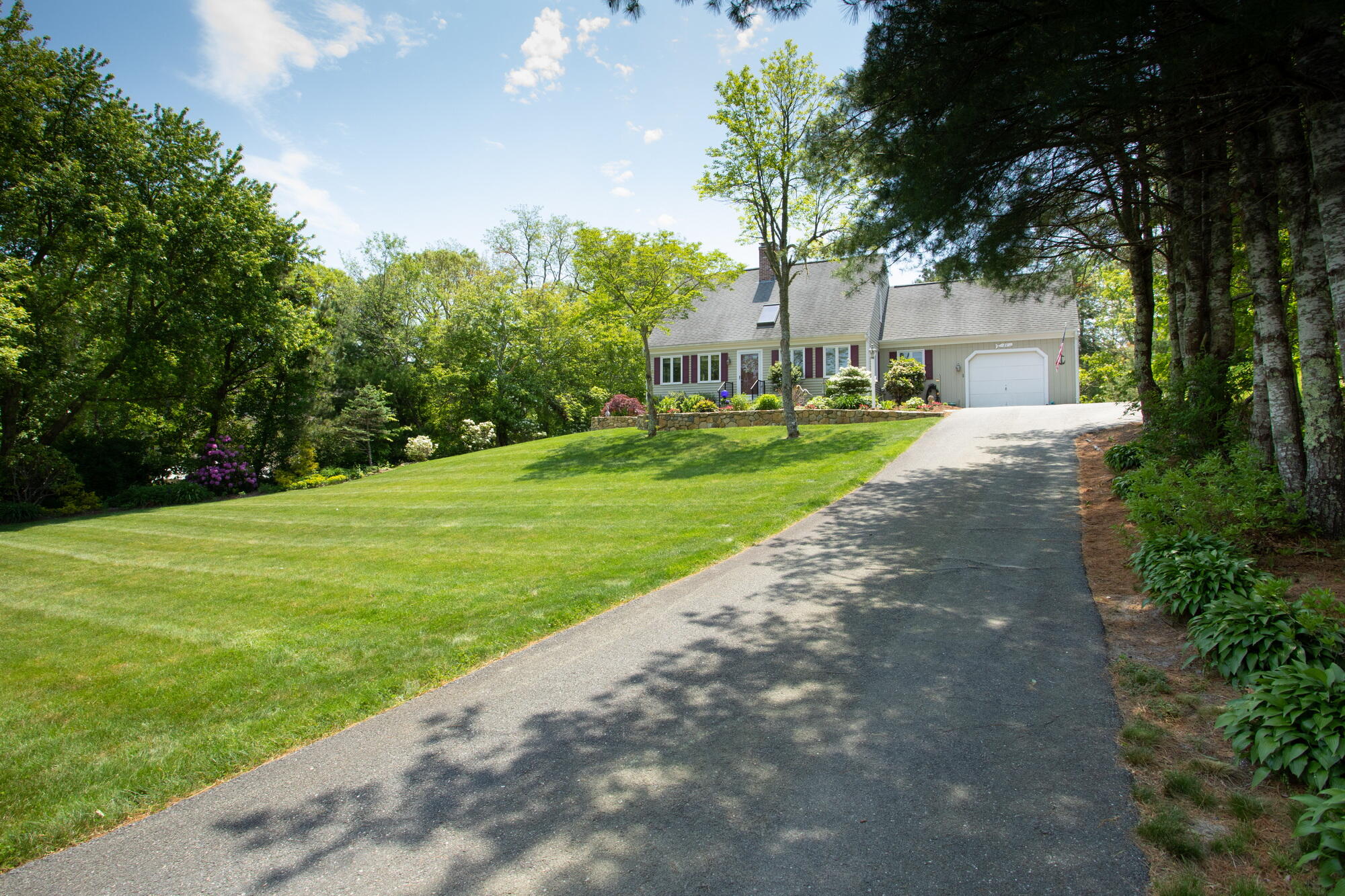 21 Captain Isiah's Road Cotuit, MA 02635 - Photo 5 of 47 a backyard of a house with plants and large trees