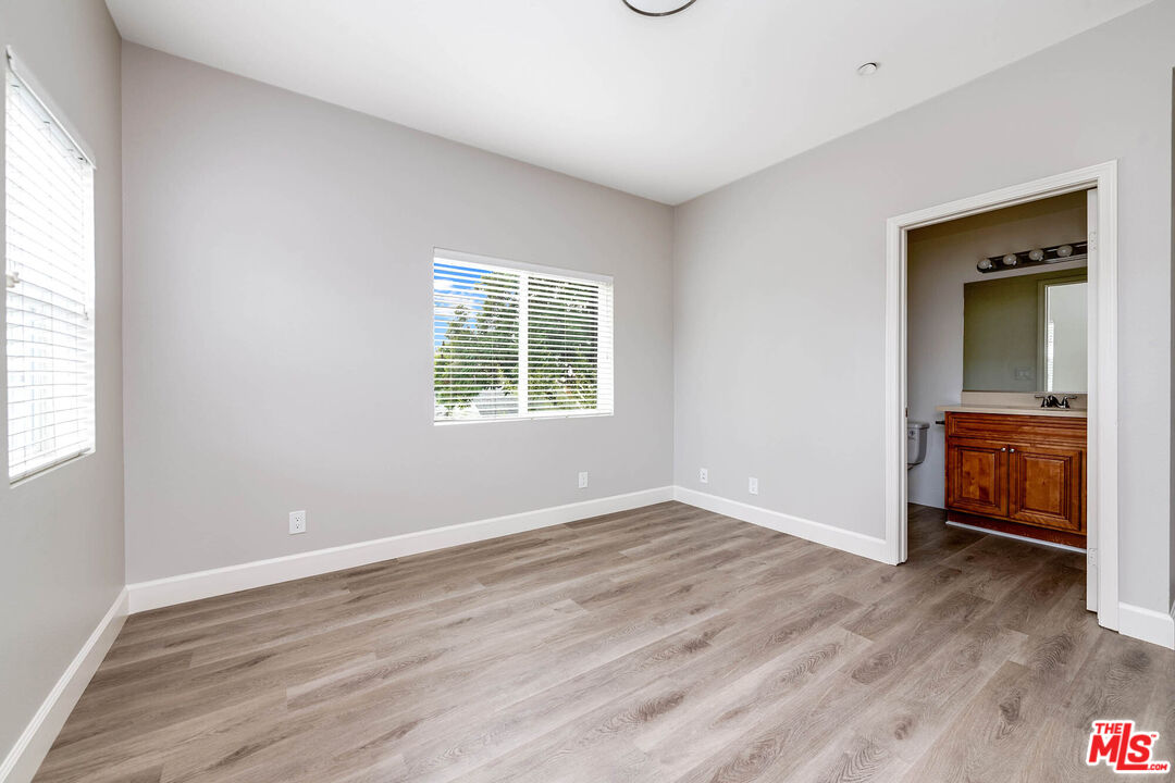 14735 Friar Street, Unit 104 Van Nuys, CA 91411 - Photo 13 of 16 an empty room with wooden floor cabinet and windows