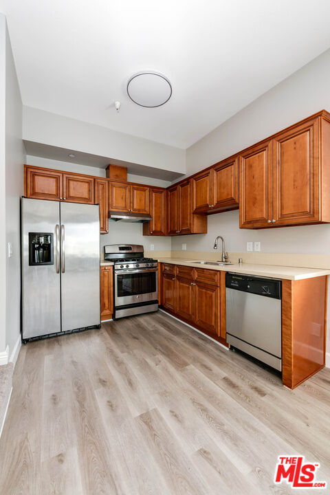 14735 Friar Street, Unit 104 Van Nuys, CA 91411 - Photo 6 of 16 a kitchen with stainless steel appliances kitchen island granite countertop a stove a sink and a refrigerator