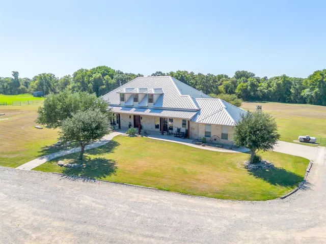 an aerial view of a house with swimming pool and large trees