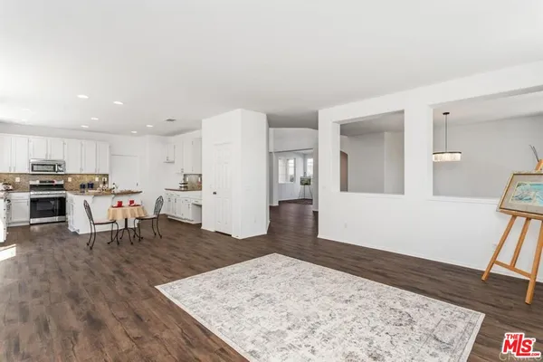 a living room with stainless steel appliances kitchen island granite countertop a refrigerator and a sink