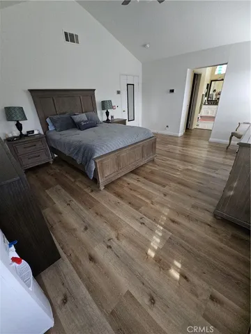 a spacious bedroom with a bed and wooden floor