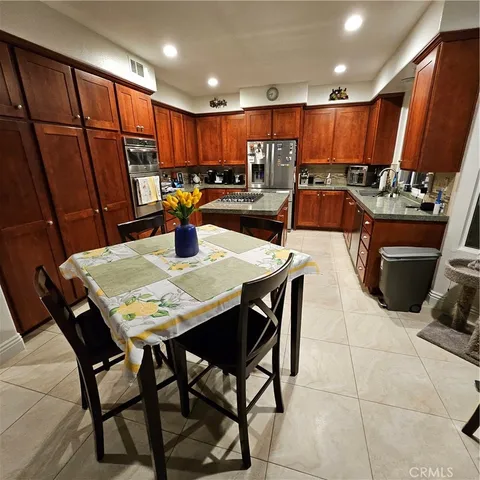 a kitchen with stainless steel appliances kitchen island granite countertop a table chairs and a refrigerator