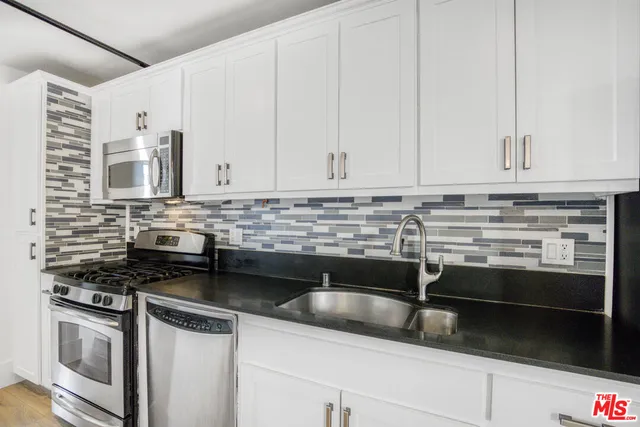 a kitchen with granite countertop white cabinets and stainless steel appliances