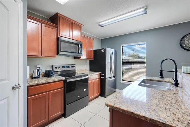 a kitchen with stainless steel appliances granite countertop a sink stove refrigerator and cabinets