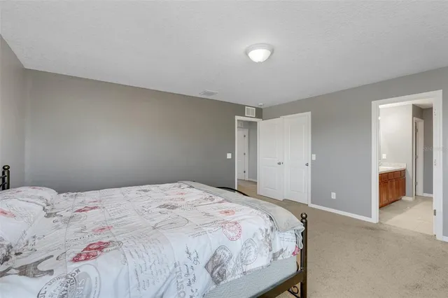 a bedroom with a large bed and a chandelier fan