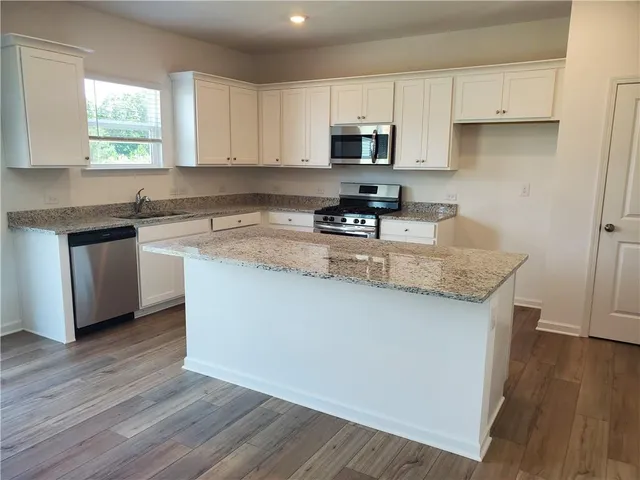 a kitchen with kitchen island granite countertop a sink cabinets and wooden floor