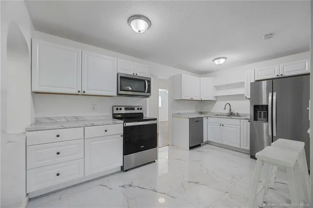 a kitchen with stainless steel appliances granite countertop a refrigerator and a sink