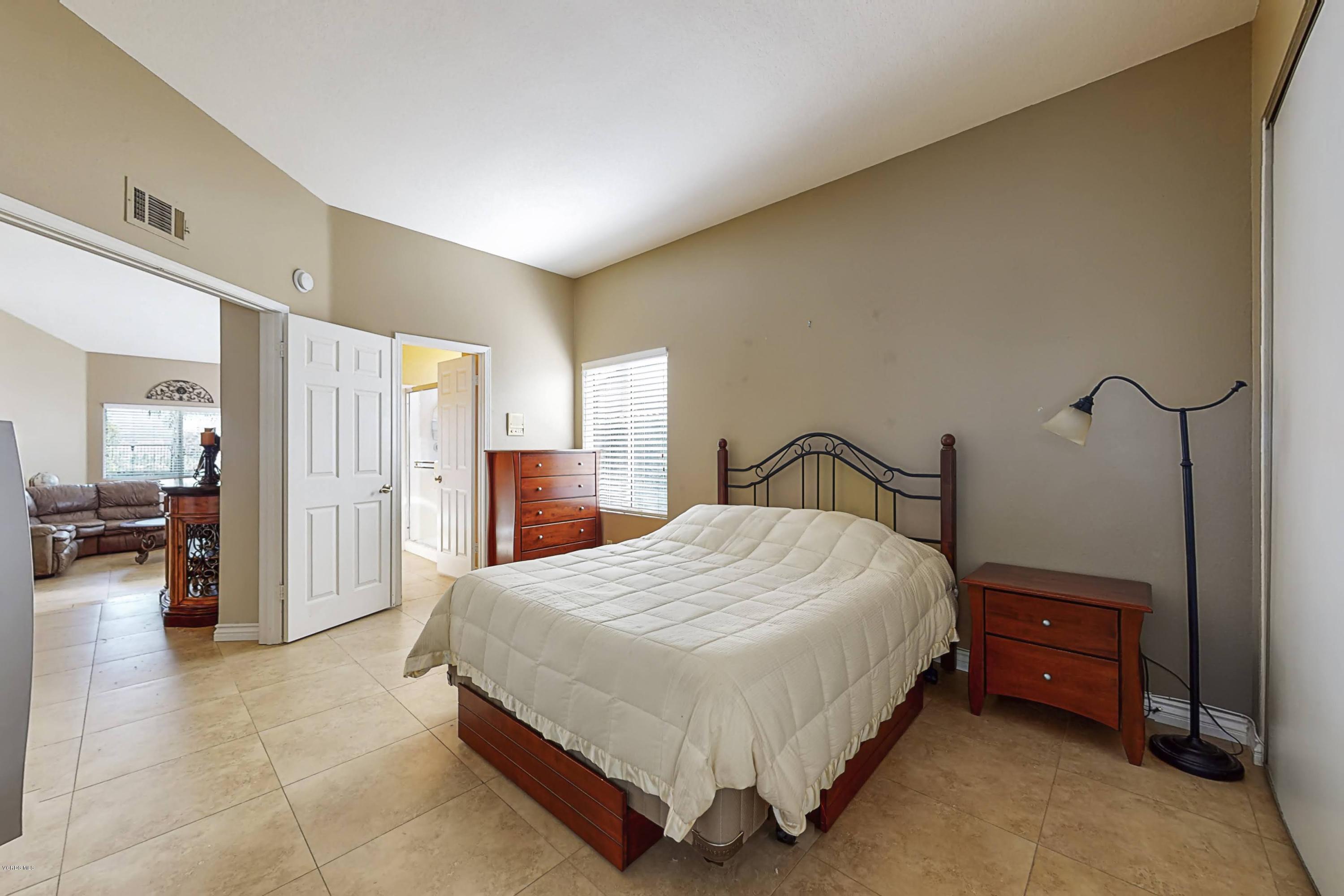 11577 Chestnut Ridge Street Moorpark, CA 93021 - Photo 26 of 58 a spacious bedroom with a bed table and a large mirror