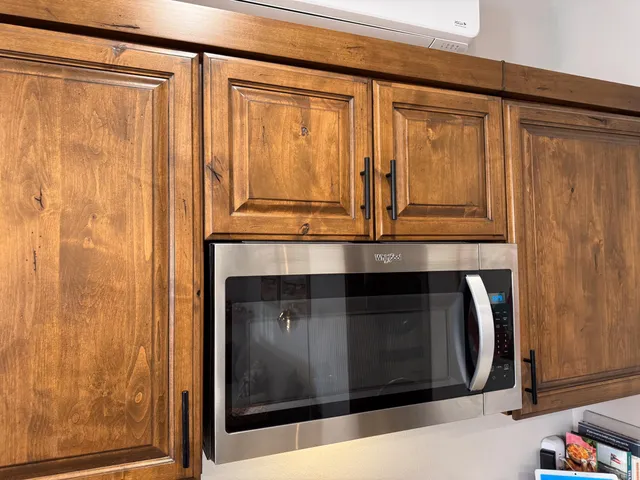 a living room with stainless steel appliances kitchen island granite countertop a sink and a flat screen tv