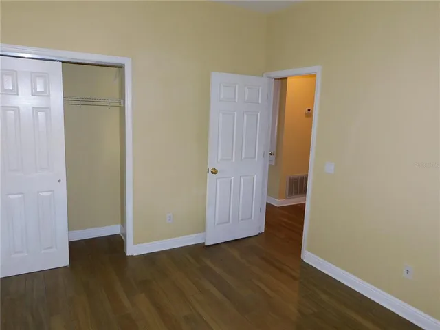an empty room with wooden floor and closet