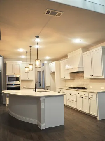 a large kitchen with stainless steel appliances kitchen island granite countertop a large counter top a sink and cabinets