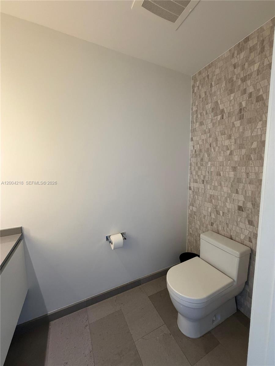68 Southeast 6th Street, Unit 2506 Miami, FL 33131 - Photo 11 of 16 a bathroom with a toilet and a mirror