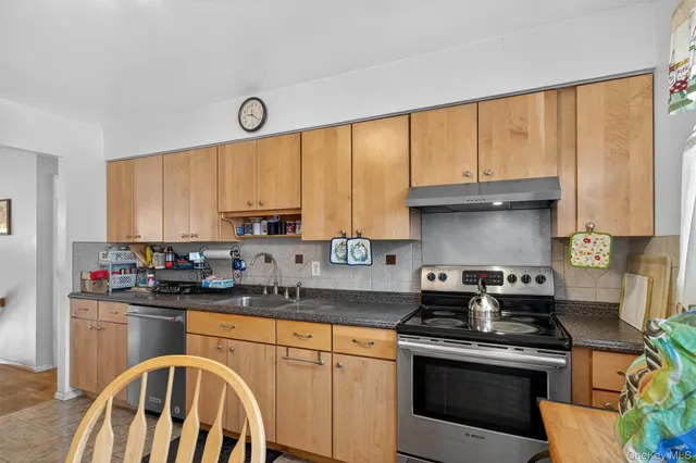 a kitchen with stainless steel appliances granite countertop a stove a sink dishwasher and white cabinets with wooden floor