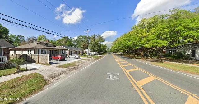 a view of a street with a bench and trees