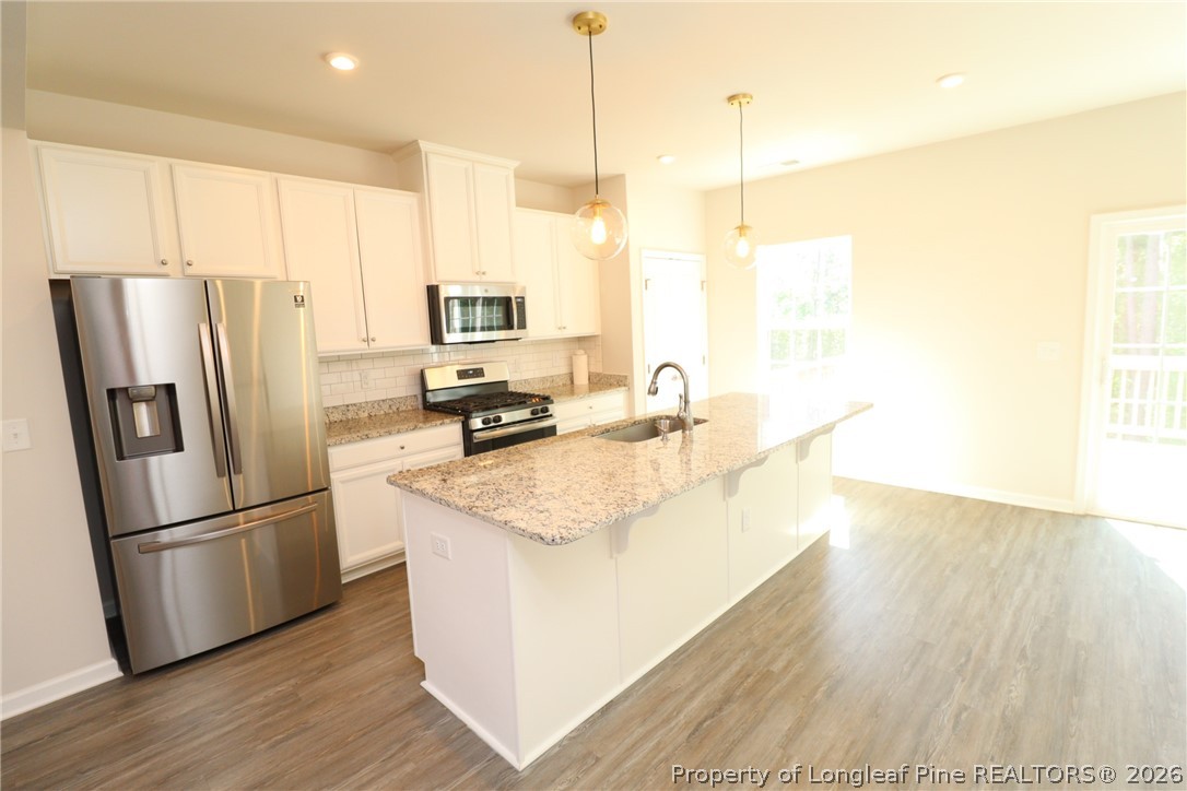 244 Amber Acorn Avenue Raleigh, NC 27603 - Photo 3 of 50 a kitchen with kitchen island a counter top space wooden floor and appliances
