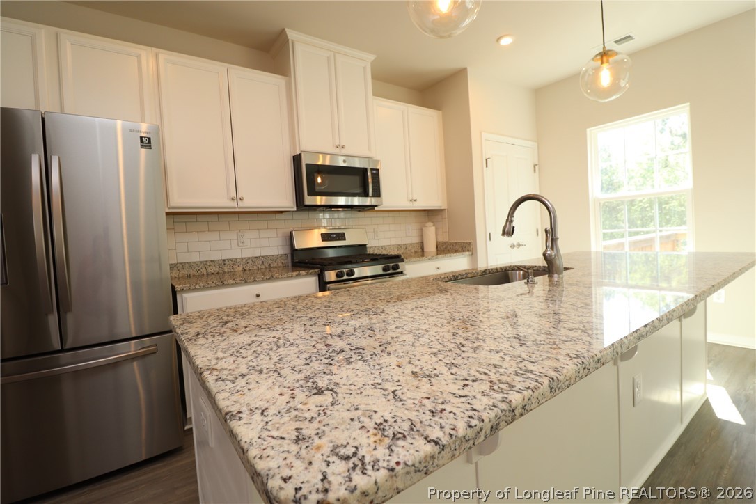 244 Amber Acorn Avenue Raleigh, NC 27603 - Photo 4 of 50 a kitchen with stainless steel appliances granite countertop a refrigerator sink and stove