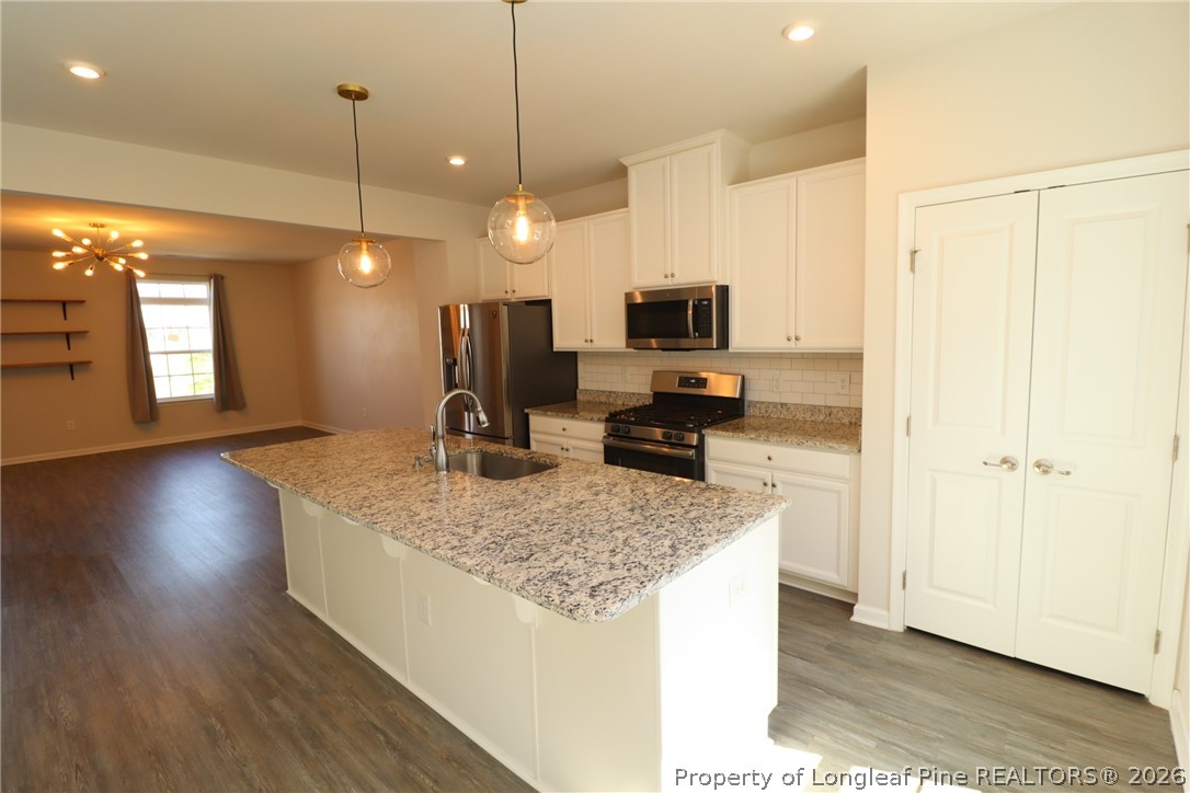 244 Amber Acorn Avenue Raleigh, NC 27603 - Photo 5 of 50 a kitchen with stainless steel appliances granite countertop a sink a stove and a wooden floor