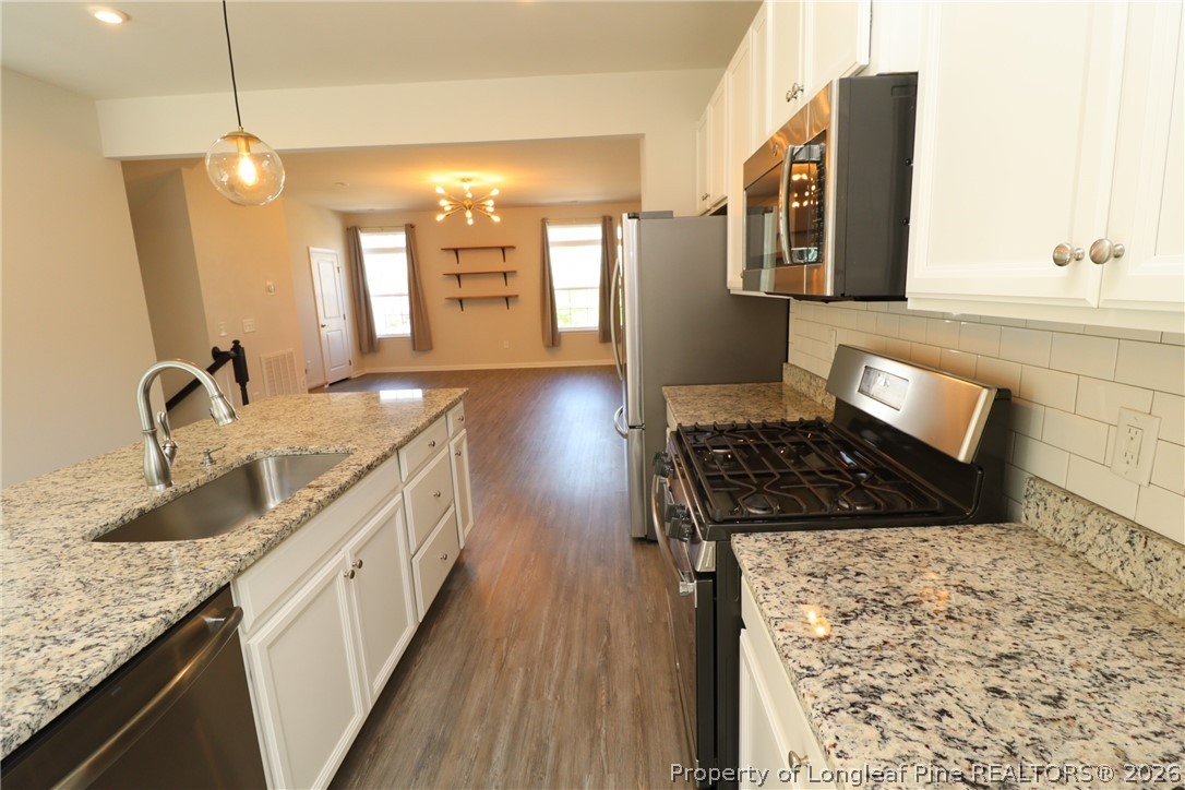 244 Amber Acorn Avenue Raleigh, NC 27603 - Photo 7 of 50 a kitchen with granite countertop a sink stove and cabinets