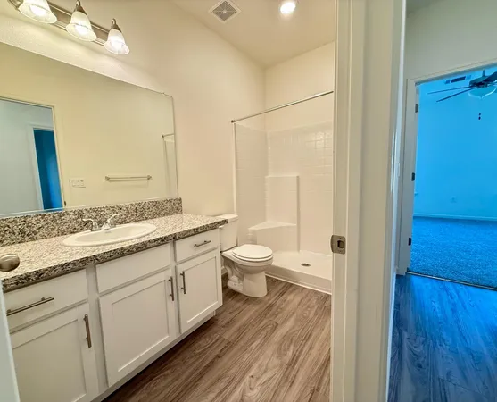 a spacious bathroom with a granite countertop sink toilet and shower