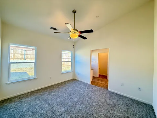 an empty room with ceiling fan and window
