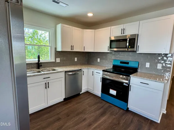 a kitchen with stainless steel appliances white cabinets a sink and a stove