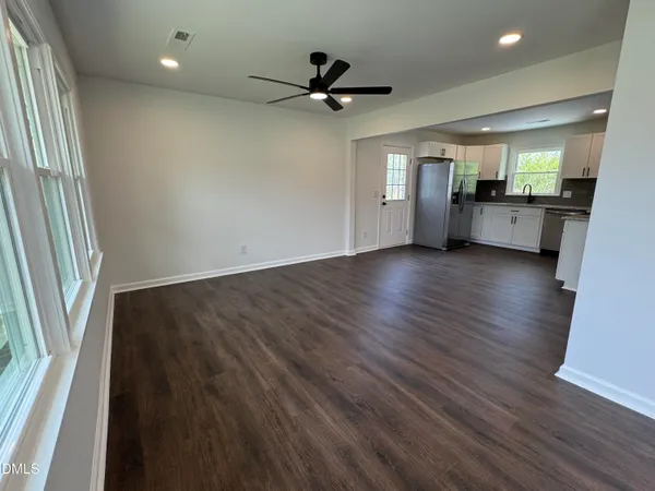 an empty room with wooden floor and a ceiling fan