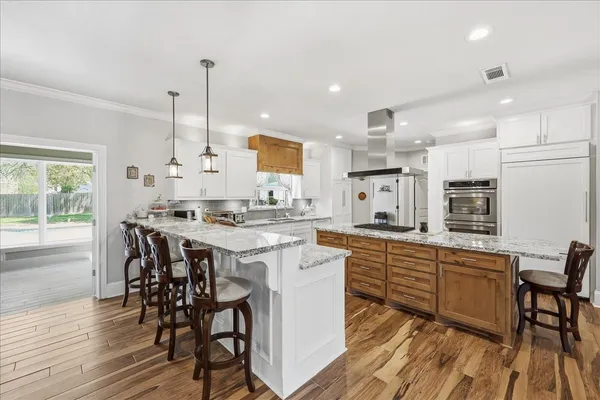a kitchen with kitchen island granite countertop wooden floors and white cabinets