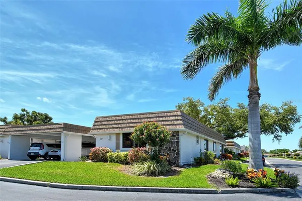 a front view of a house with a garden and trees