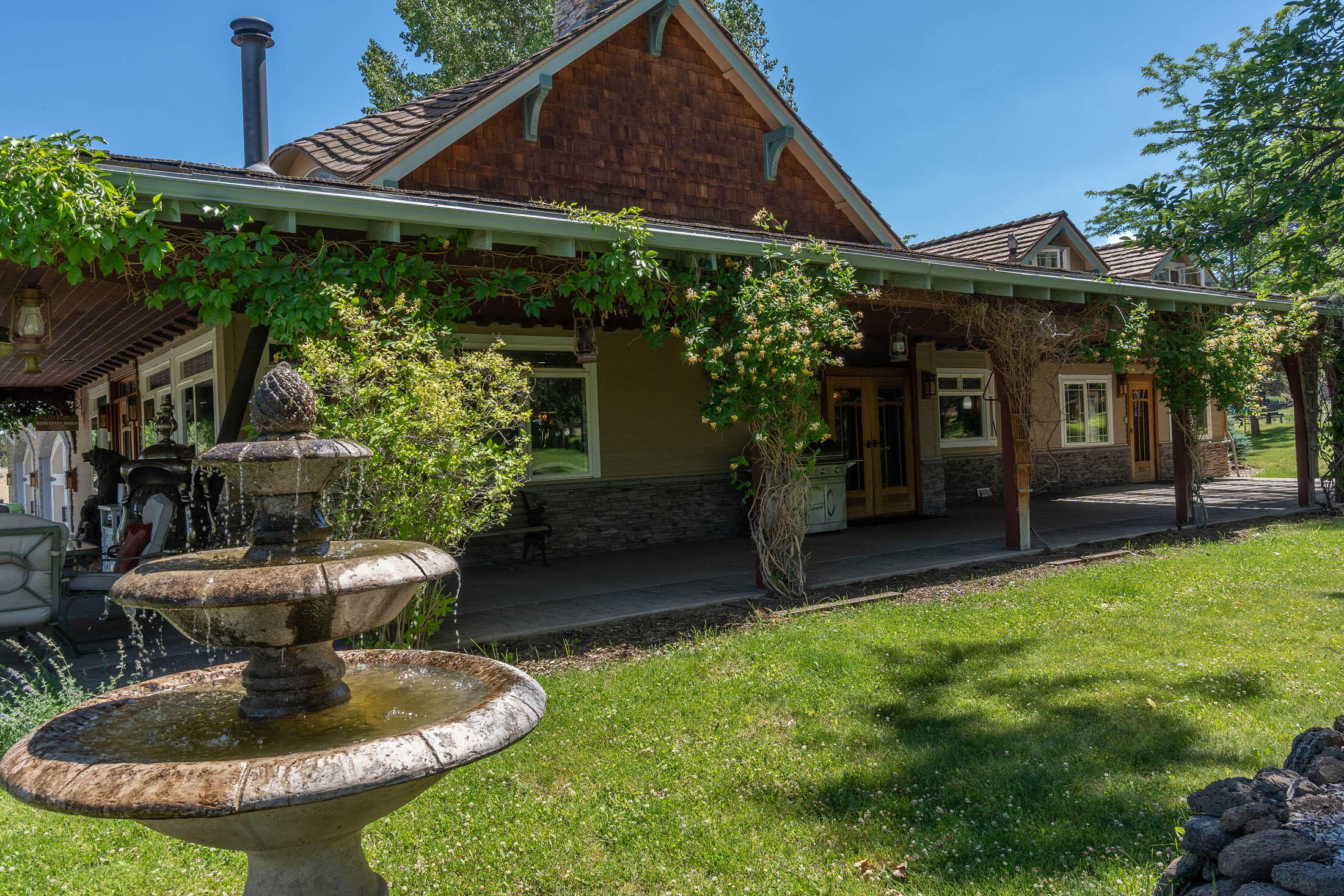 21925 Bear Creek Road Bend, OR 97702 - Photo 58 of 104 Water fountain in the front of the house with nearly wrap-around concrete porch. Beautifully landscaped.