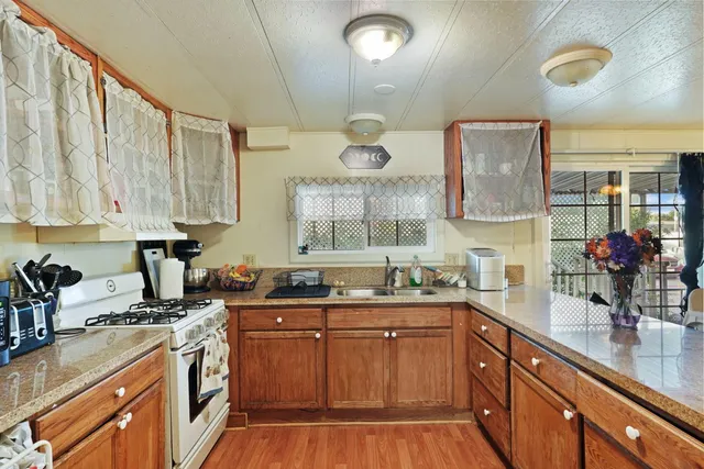 a kitchen with stainless steel appliances granite countertop a sink a stove and a wooden cabinets