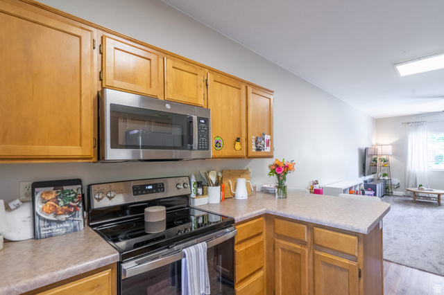 700 North Main Street, Unit F3 Washington, UT 84780 - Photo 10 of 34 Kitchen featuring wood cabinetry, stainless steel microwave, electric range, and laminate countertops