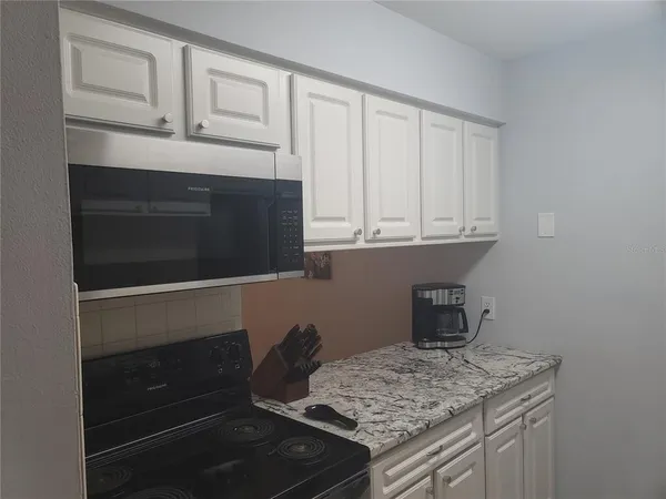 a kitchen with granite countertop white cabinets and white appliances