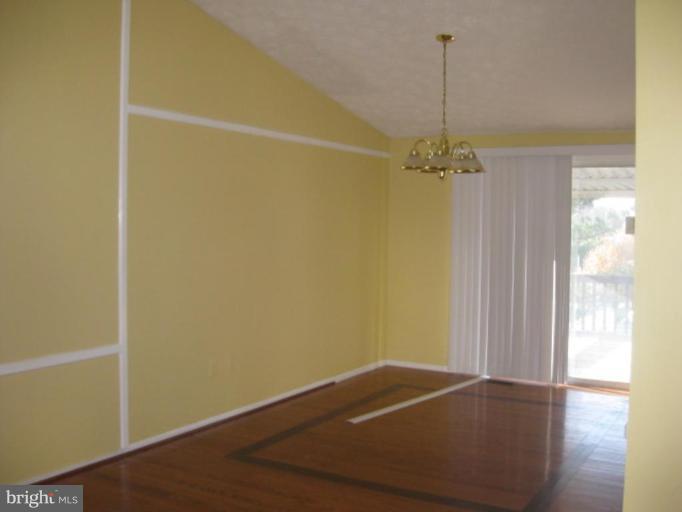 100 Sandhill Road Essex, MD 21221 - Photo 3 of 10 a view of a room with wooden floor a ceiling fan and windows
