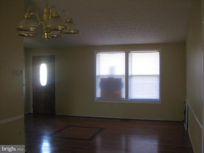 100 Sandhill Road Essex, MD 21221 - Photo 4 of 10 an empty room with wooden floor and windows