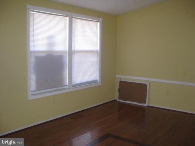100 Sandhill Road Essex, MD 21221 - Photo 5 of 10 a view of an empty room with wooden floor and a window