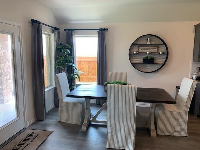 712 Feldspar Way Princeton, TX 75407 - Photo 10 of 12 Dining area featuring wood-finish flooring, two large windows with dark drapery, and a glass-paneled door