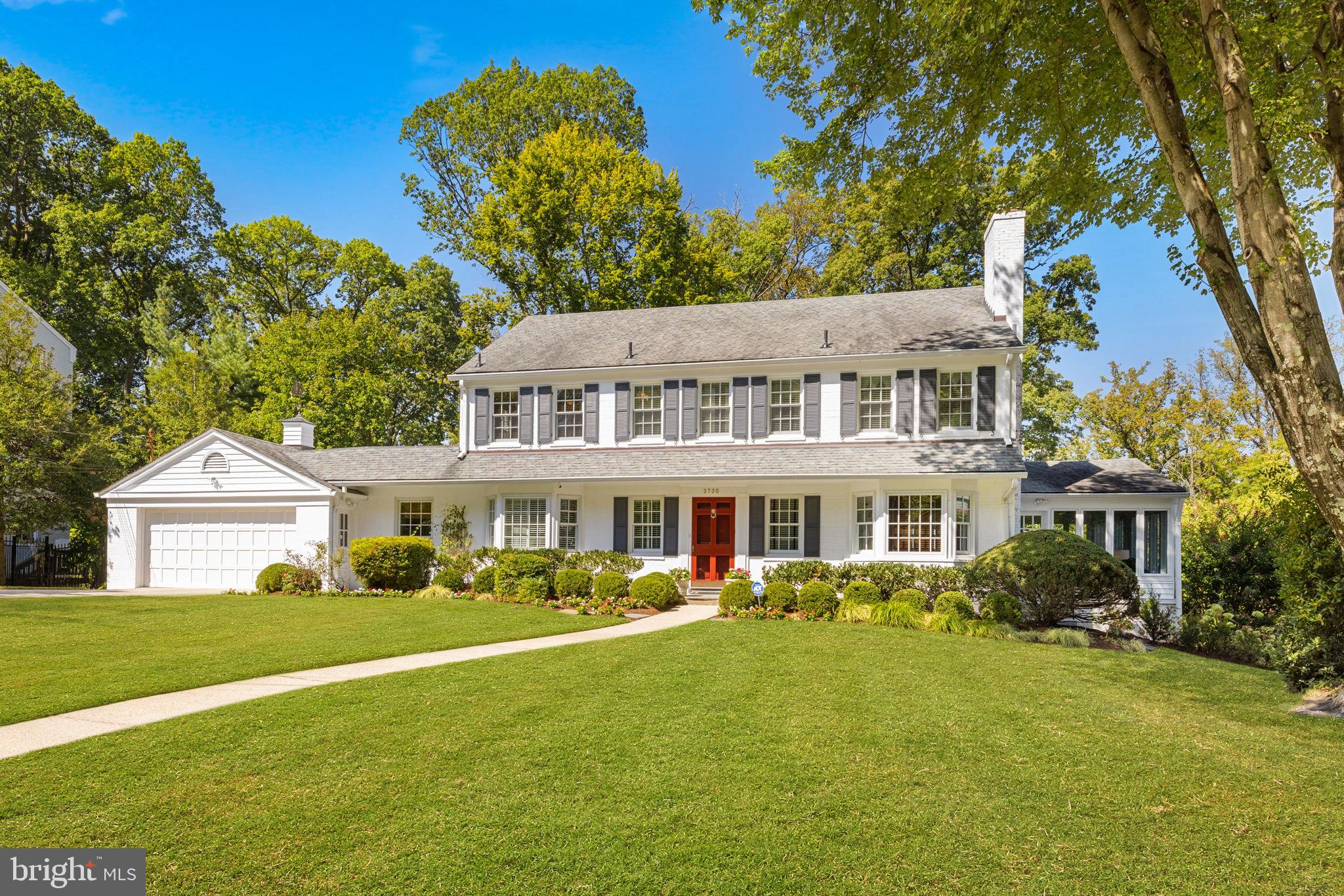 a front view of a house with a garden and trees