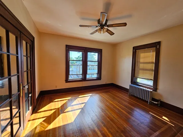 a view of an empty room with a window and wooden floor