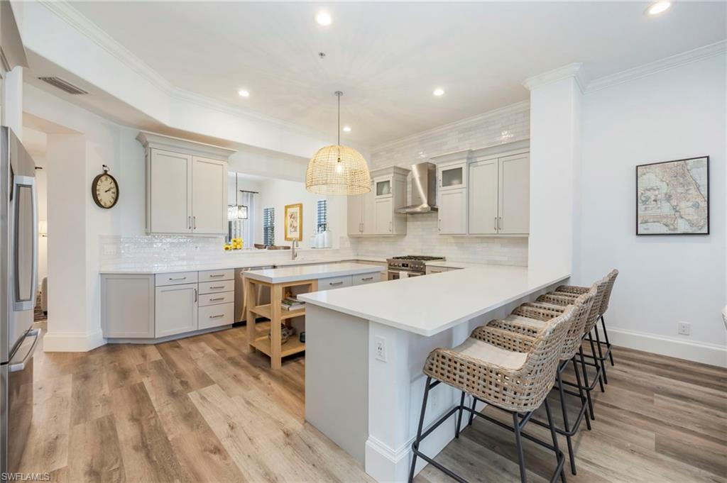 2870 Castillo Court, Unit 103 Naples, FL 34109 - Photo 3 of 34 a kitchen with a sink cabinets and wooden floor
