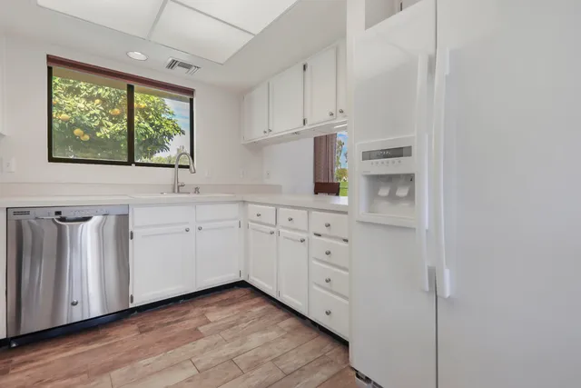 a kitchen with white cabinets and wooden floors