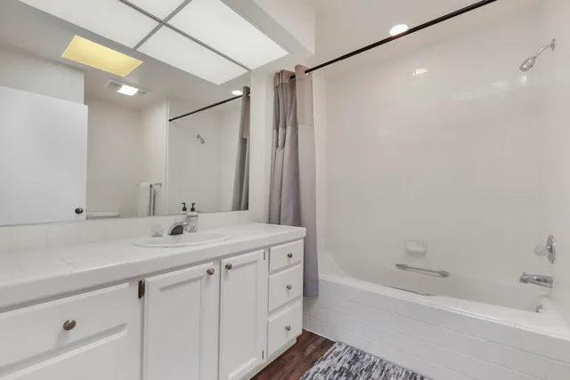 a bathroom with a tub sink vanity granite and a mirror