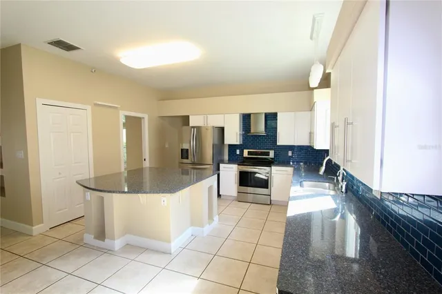 a large white kitchen with a large window and stainless steel appliances