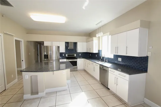 a large kitchen with granite countertop a stove a sink dishwasher and a refrigerator