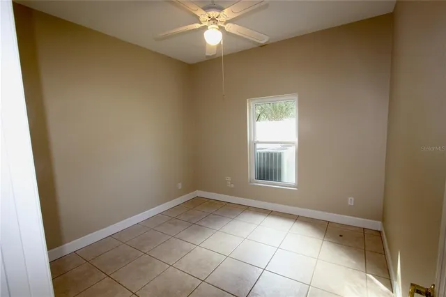 an empty room with a chandelier fan and windows