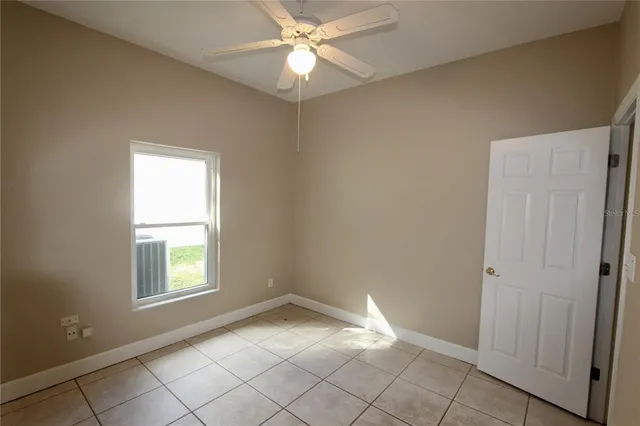 an empty room with windows and fan