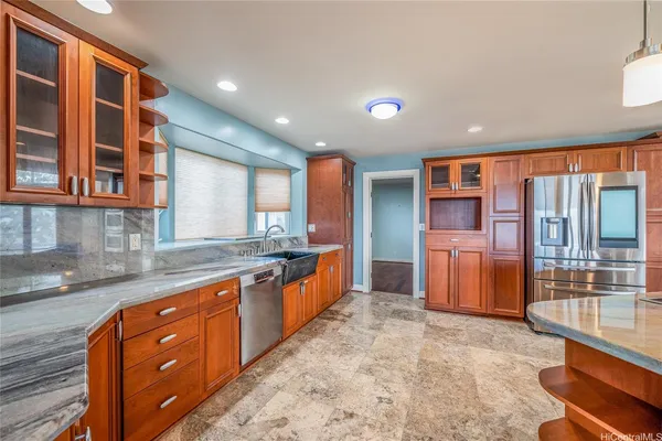 a large kitchen with stainless steel appliances a large counter top a stove a sink and a refrigerator