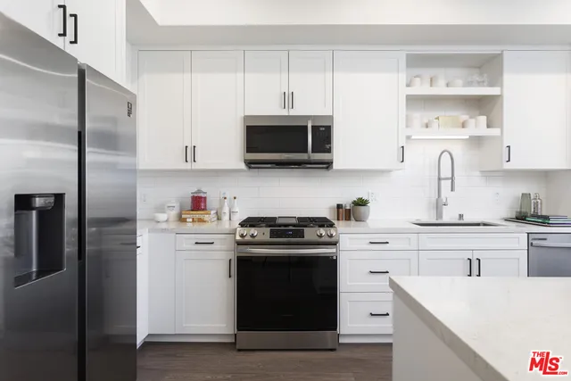 a kitchen with stainless steel appliances granite countertop a stove a sink and a refrigerator